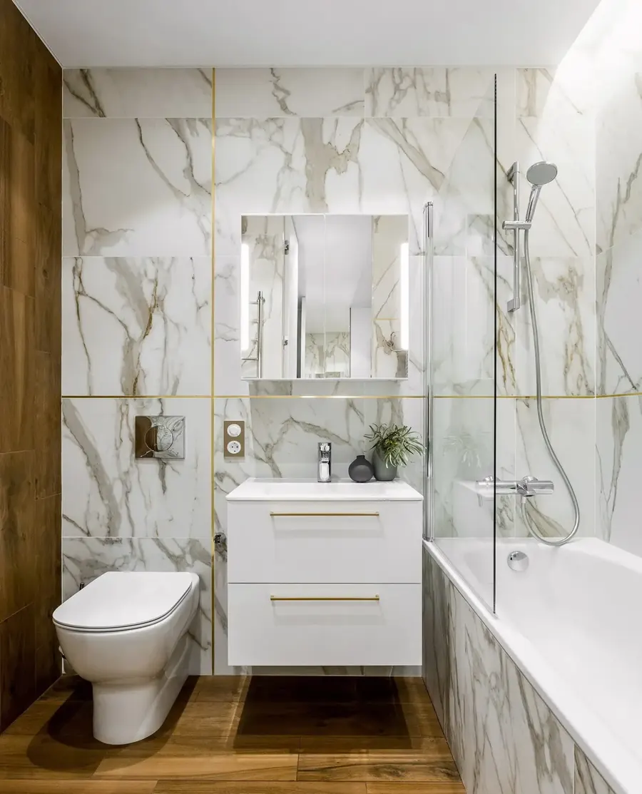 Bathroom with white marble-look wall tile and a tub with a glass screen