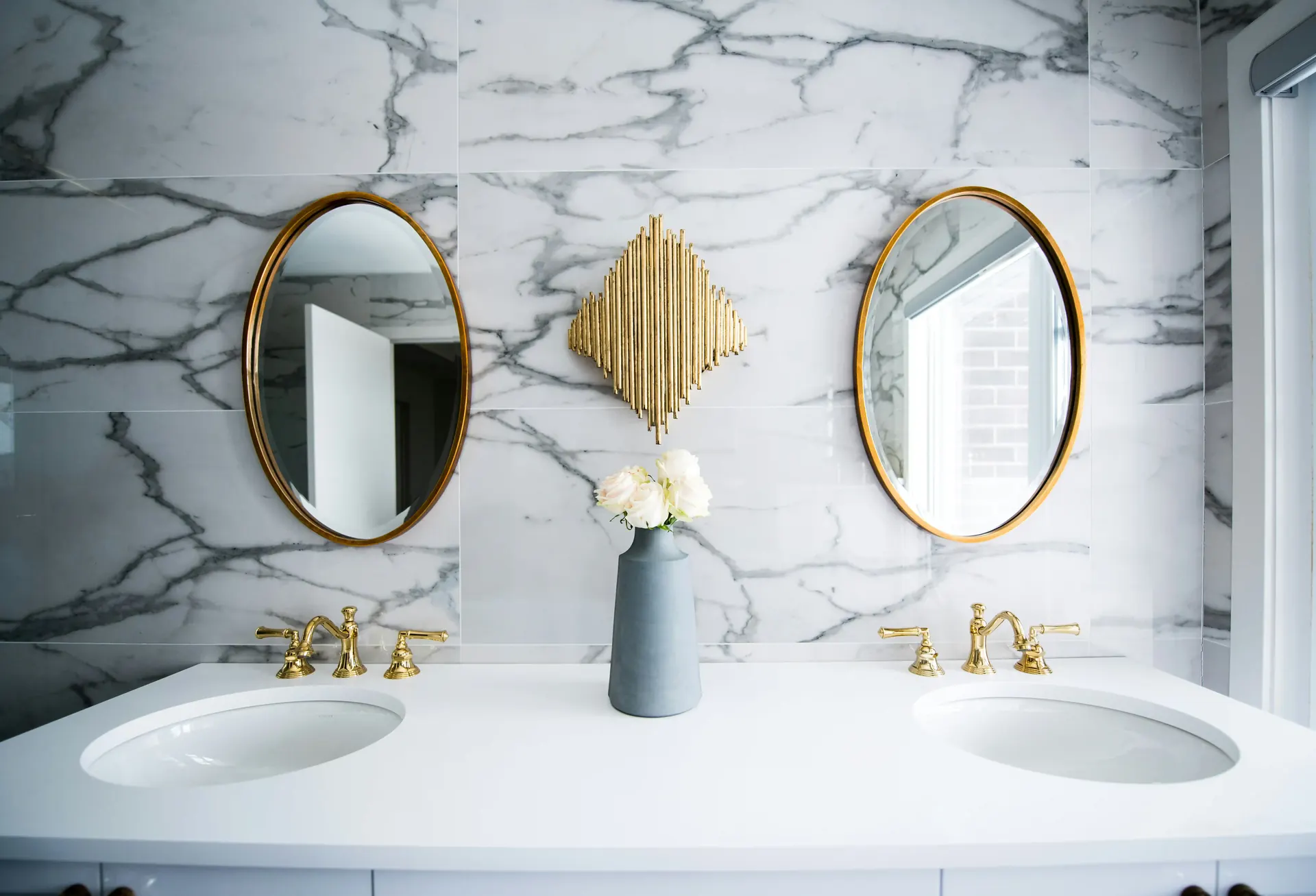 Marble-look tile bathroom with a double vanity and round mirrors
