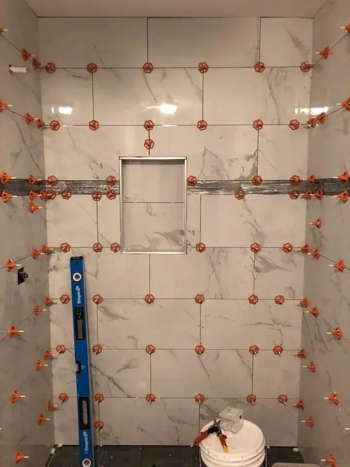 Leveling clips holding large wall tiles flat during installation