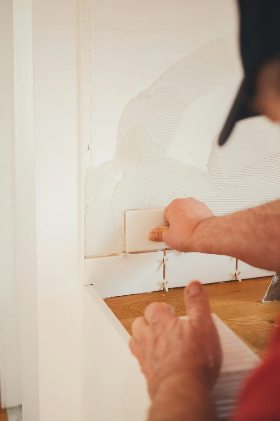 Installer pressing a tile into place on a fresh mortar bed